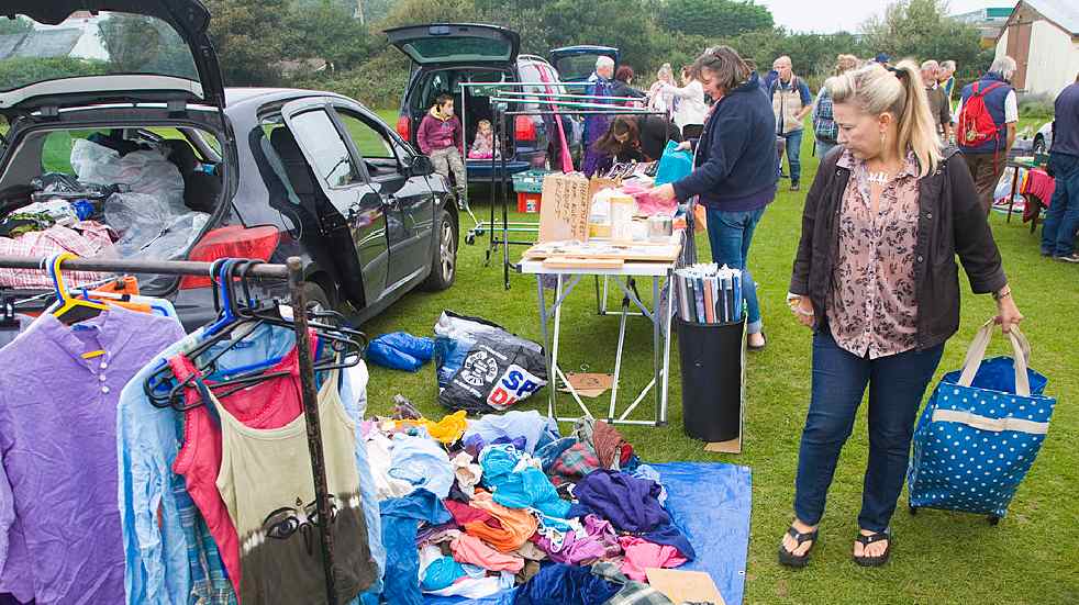 How to do a car boot sale woman looking at clothes on floor car boot sale